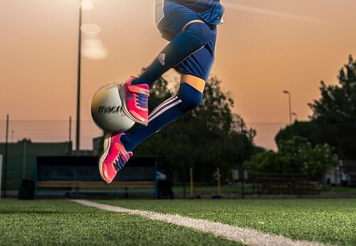 Kind springt mit einem Fußball in die Luft