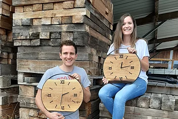 Ein paar präsentiert zwei Holz-Wanduhren