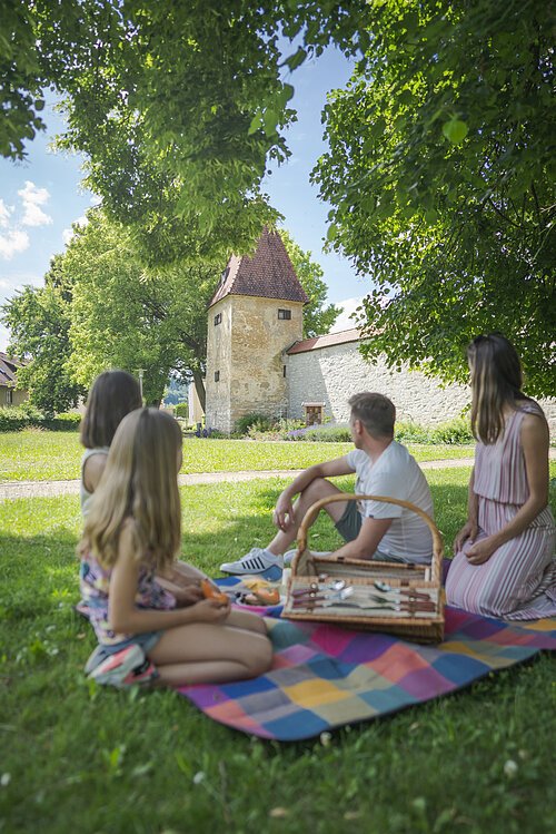 Das Bild zeigt eine Familie beim Picknick in der Heinrich-Herold-Anlage. Im Hintergrund sieht man die Gredinger Stadtmauer mit dem Zeidlerturm.