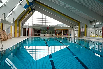 Innenansicht des Gredinger Hallenbads mit großen Fenstern und blauen Fliesen im Beckenboden