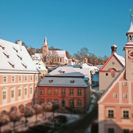Schneebedeckte Dächer und Kirchtürme in einer kleinen Stadt bei klarem Himmel am Wintertag.