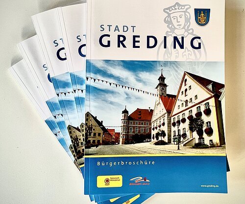 Bürgerbroschüre Stadt Greding Bürgerbroschüre mit Bild eines historischen Gebäudes und blauem Himmel, gestapelt auf weißem Untergrund
