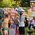 Drei Kinder mit Schutzmasken sprühen bunte Graffiti auf eine große weiße Wand im Freien.